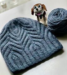 a knitted hat and ball of yarn next to a toy dog on a table