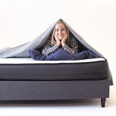 a woman laying on top of a bed with a tent over her head