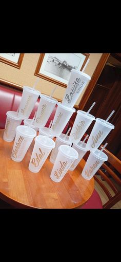 plastic cups sitting on top of a wooden table next to red booth seats in a restaurant