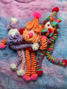 three crocheted stuffed animals laying on top of a blue blanket