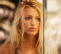 a woman with long blonde hair looking at the camera