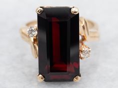 This elegant yellow gold ring features a stunning emerald cut garnet with diamond accents. The bypass design adds a unique touch, making it a perfect statement piece for both casual and formal occasions. Adorn your finger with its rich color and sparkling diamonds! Metal: 14K Yellow Gold Gem: Garnet 11.75 Carats Gem Measurements: 9.1 x 17.1 mm, Emerald Cut Accents: 2 Diamonds totaling .10 Carats, VS in Clarity, H in Color Ring Size: 6 Marks: "B&F 14K" Stamped on the inside band SKU #: A42979 Each piece has been identified and graded by a Graduate Gemologist who has been certified by the Gemological Institute of America (GIA). We have six brick-and-mortar storefronts in Maine, Massachusetts, and New Hampshire and have been in business for over 25 years! Please visit our Shop's About Page or Garnet Statement Ring, Gold Garnet Ring, Bypass Ring, Ring With Diamond, Garnet Ring, January Birthstone, Garnet Rings, Color Ring, Yellow Gold Ring