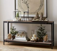 two shelves with christmas decorations and candles on them in front of a framed art piece