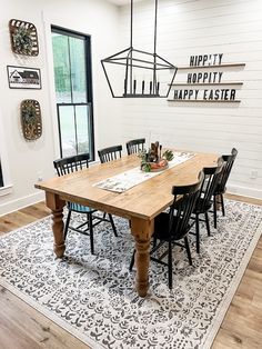 a dining room table with black chairs and a white rug