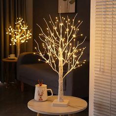 a lighted tree on a table in a living room