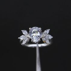 an engagement ring with three pear shaped diamonds in the center and leaves on each side