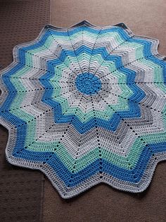 a blue and white crocheted doily sitting on the floor next to a couch