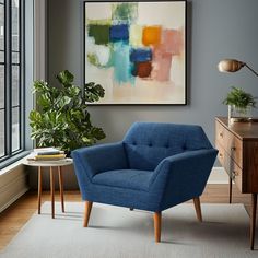 a blue chair sitting in front of a window next to a table with a potted plant