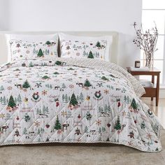 a white bed with christmas themed comforter and pillows