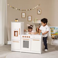 two children playing in a play kitchen set