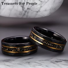 two black and gold wedding bands with white marble in the background that says treasures for people