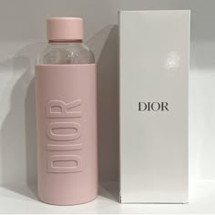 a pink dior bottle next to a white box with the word dior printed on it