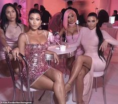 three women sitting at a table in pink dresses