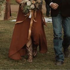 a woman in a brown dress and cowboy boots is walking down the aisle with her groom