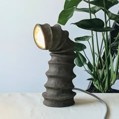 a lamp that is on top of a table next to a potted plant and some plants