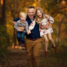 a man and two young children are running through the woods with their arms around each other