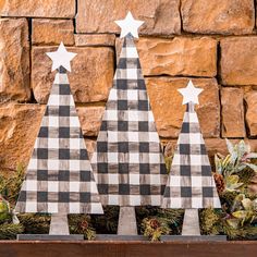 three wooden christmas trees in front of a brick wall