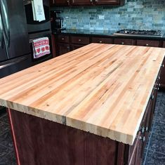 a kitchen island made out of wood in front of a refrigerator