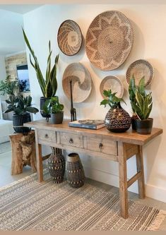 a wooden table topped with potted plants next to a wall covered in wicker baskets