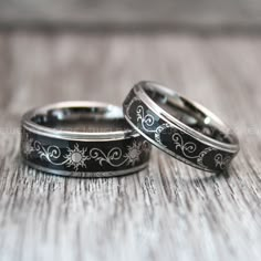 two wedding rings sitting on top of a wooden table next to each other with floral designs