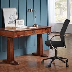 an office chair sits next to a desk in front of a blue wall and wooden floor