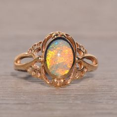 The Aputula: Australian Opal Ring In Yellow Gold. At The Heart Of This Ring Lies An Oval Cabochon Natural Australian Opal, Skillfully Bezel-Set In A North To South Orientation, Showcasing Its Mesmerizing Play Of Color From Every Angle. Encircling The Opal Is An Intricate Filigree Pattern, Which Extends Gracefully Down The Shank, Adding An Extra Layer Of Elegance To The Design. Crafted With Precision In 14 Karat Yellow Gold, This Ring Radiates Warmth And Sophistication. Currently Sized At 5.25, It Can Be Adjusted To Fit Any Finger Size Upon Request For An Additional Charge, Ensuring A Perfect And Comfortable Fit For The Wearer. Vintage Opal Engagement Ring Victorian, Vintage Opal Engagement Ring, Intricate Rings, Australian Opal Ring, Victorian Engagement Rings, Filigree Pattern, Bezel Set Ring, Engagement Rings Opal, Cabochon Ring