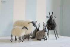 three sheep are standing next to each other on a white surface with striped wallpaper