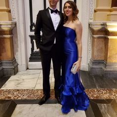 a man in a tuxedo and a woman in a blue dress pose for the camera