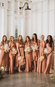 a group of women standing next to each other holding bouquets in front of them