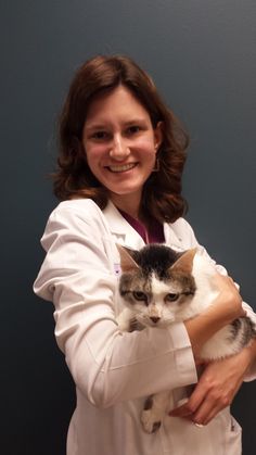 a woman in white lab coat holding a cat