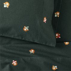 the bedding is made up with black sheets and brown bears on them, as well as two pillow cases