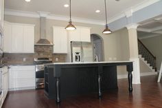 an empty kitchen with white cabinets and black island in the center, surrounded by wood flooring