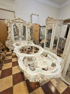 a room filled with lots of white furniture and mirrors on top of wooden flooring