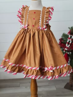 Girls Gingerbread Dress Adorable girls Gingerbread Dress! Features fun trim and ties in back. Christmas Shift Dress, Gingerbread Christmas Dress, Fitted Ruffle Holiday Dress For Dress-up, Fitted Ruffle Holiday Dress For Dress-up Events, Formal Fitted Ruffle Holiday Dress, Sleeveless Ruffled Holiday Dress, Fitted Christmas Holiday Dress With Ruffles, Fitted Christmas Dress With Ruffles, Fitted Holiday Dress With Ruffles For Christmas