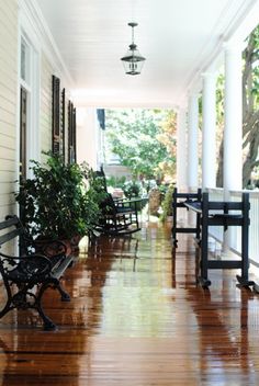 the front porch is lined with benches and potted plants