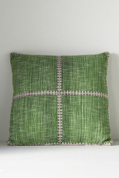 a green and pink pillow sitting on top of a white shelf