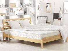 a bed with white sheets and pillows in a room filled with bookshelf shelves