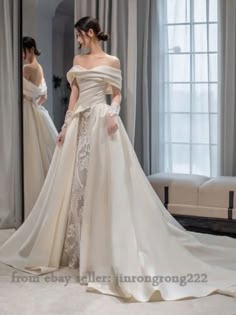 a woman in a white wedding dress standing next to a mirror