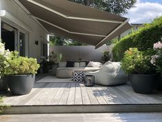 an outdoor living area with couches and potted plants on the side of it