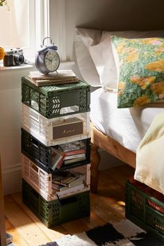 a stack of books sitting on top of a wooden floor next to a bed in a bedroom