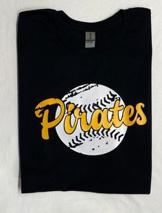 a black t - shirt with the word pirates on it and a baseball in yellow