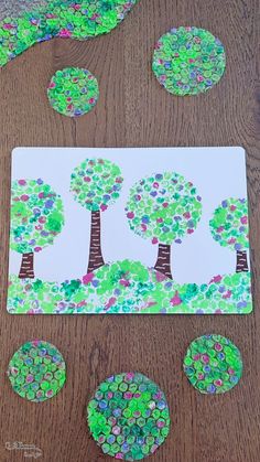 the paper plate is made to look like trees and circles with buttons on them, sitting on a wooden table