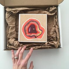 a hand is reaching for a piece of artwork in a box