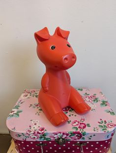 an orange pig sitting on top of a pink suitcase