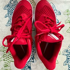 a pair of red tennis shoes sitting on top of a table