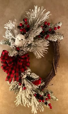 a christmas wreath hanging on the wall with red berries and pineconis around it