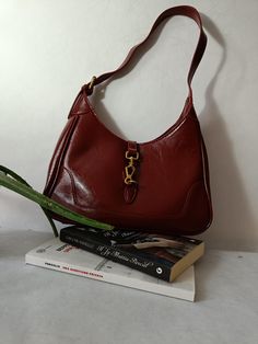 This vegan leather bag is an elegant and versatile accessory, perfect for any occasion. Crafted from burgundy leather, it stands out for its classic half-moon design, combining style and functionality. The closure is enriched with a gold metal detail, which adds a touch of sophistication. The bag's simple, clean lines make it suitable for both casual and formal wear. The shoulder strap is comfortable and durable, providing convenience for everyday use. Ideal for those who love vintage style, this bag goes perfectly with any outfit, adding a sophisticated touch. Retro Burgundy Shoulder Bag, Retro Burgundy Bags For Daily Use, Retro Burgundy Shoulder Bag For Daily Use, Trendy Burgundy Shoulder Bag For Everyday, Trendy Everyday Burgundy Shoulder Bag, Burgundy Satchel Shoulder Bag For Fall, Vintage Burgundy Shoulder Bag For Everyday, Vintage Burgundy Shoulder Bag With Adjustable Strap, Retro Burgundy Satchel Shoulder Bag