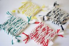 four knitted pieces of cloth on a white surface with red, yellow and green yarn