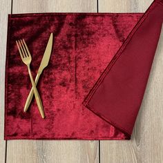 a fork and knife on top of a red napkin with a gold utensil