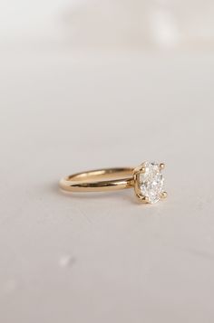 a gold ring with a single diamond in it on a white surface, close up